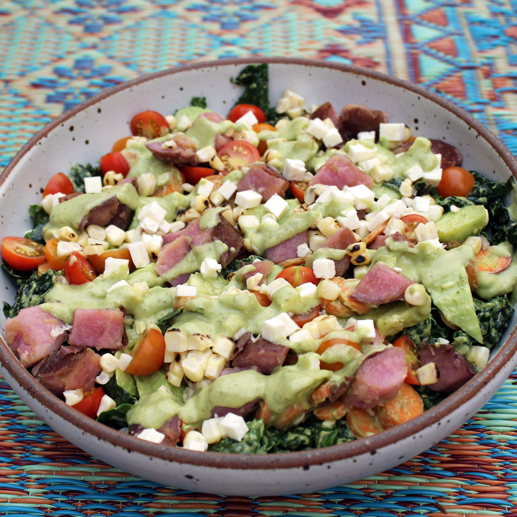 avocado poblano green goddess dressing is used on a salad featuring kale, feta, purple potatoes and tomato