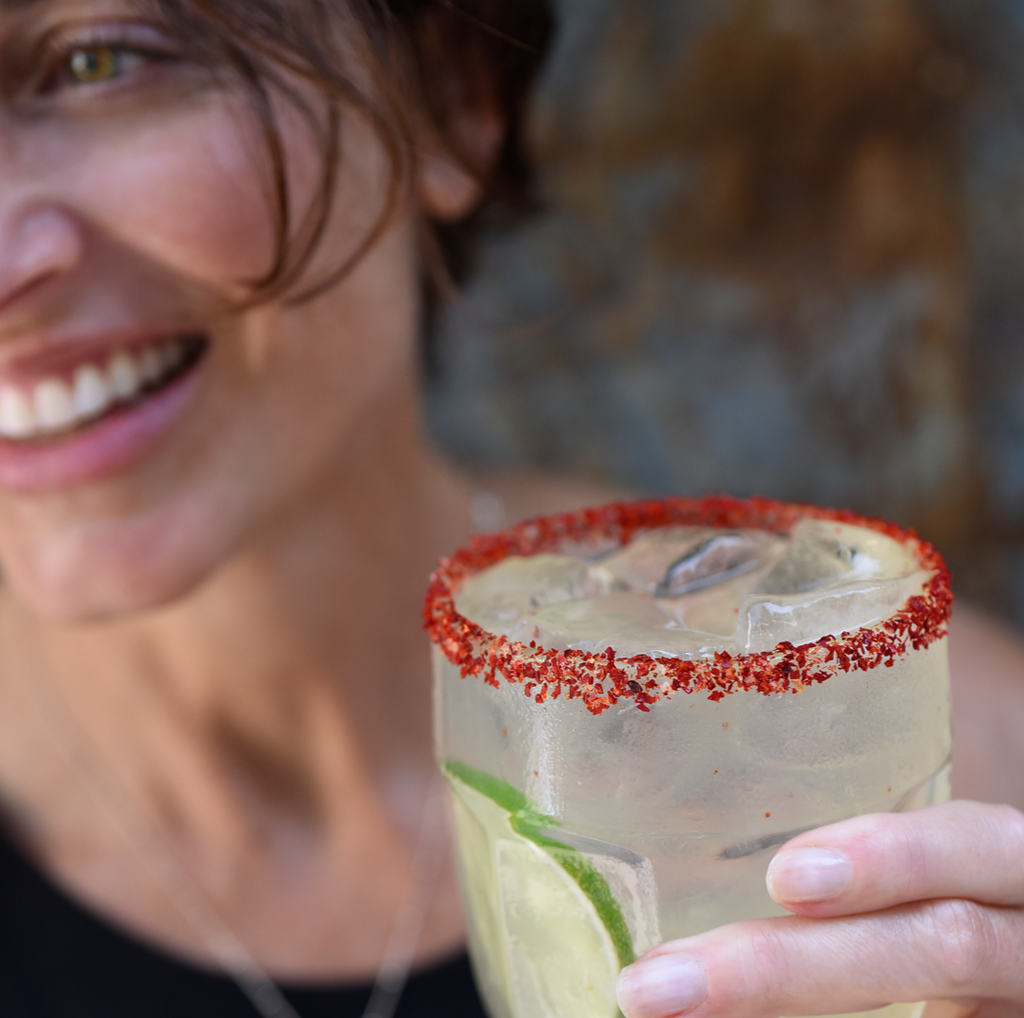 person holding glass filled with margarita and chile rim