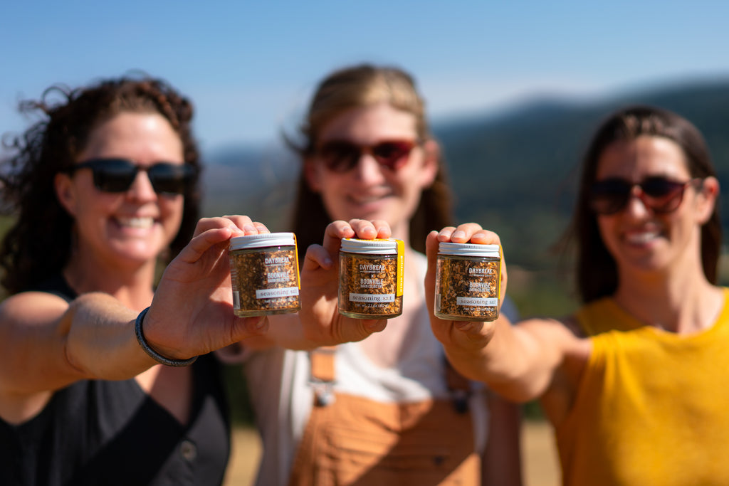 three women holding jars of chile powder