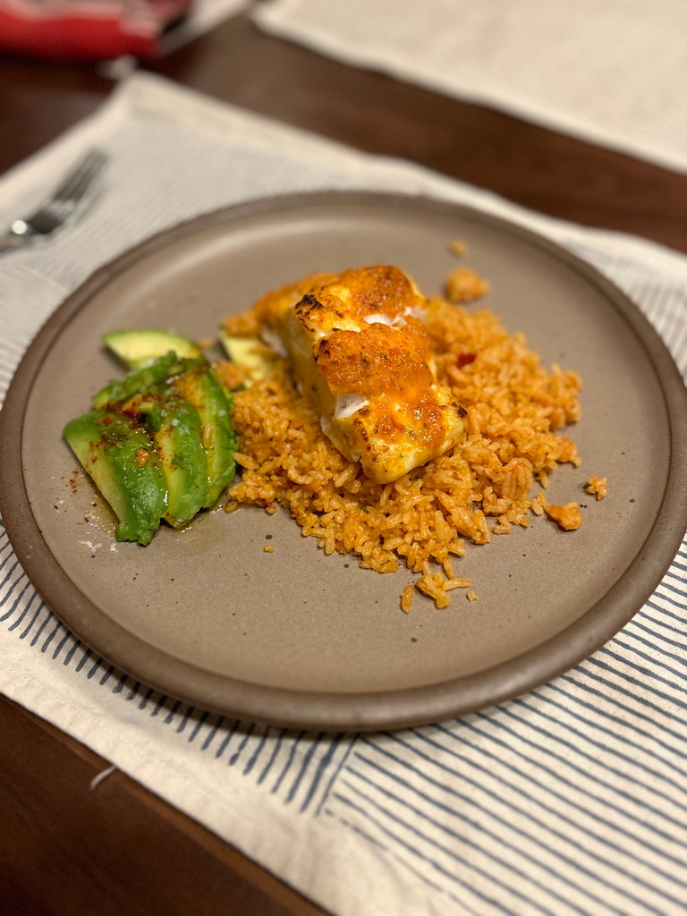 Plate with spanish rice, a filet of roasted fish, salsa, and avocado