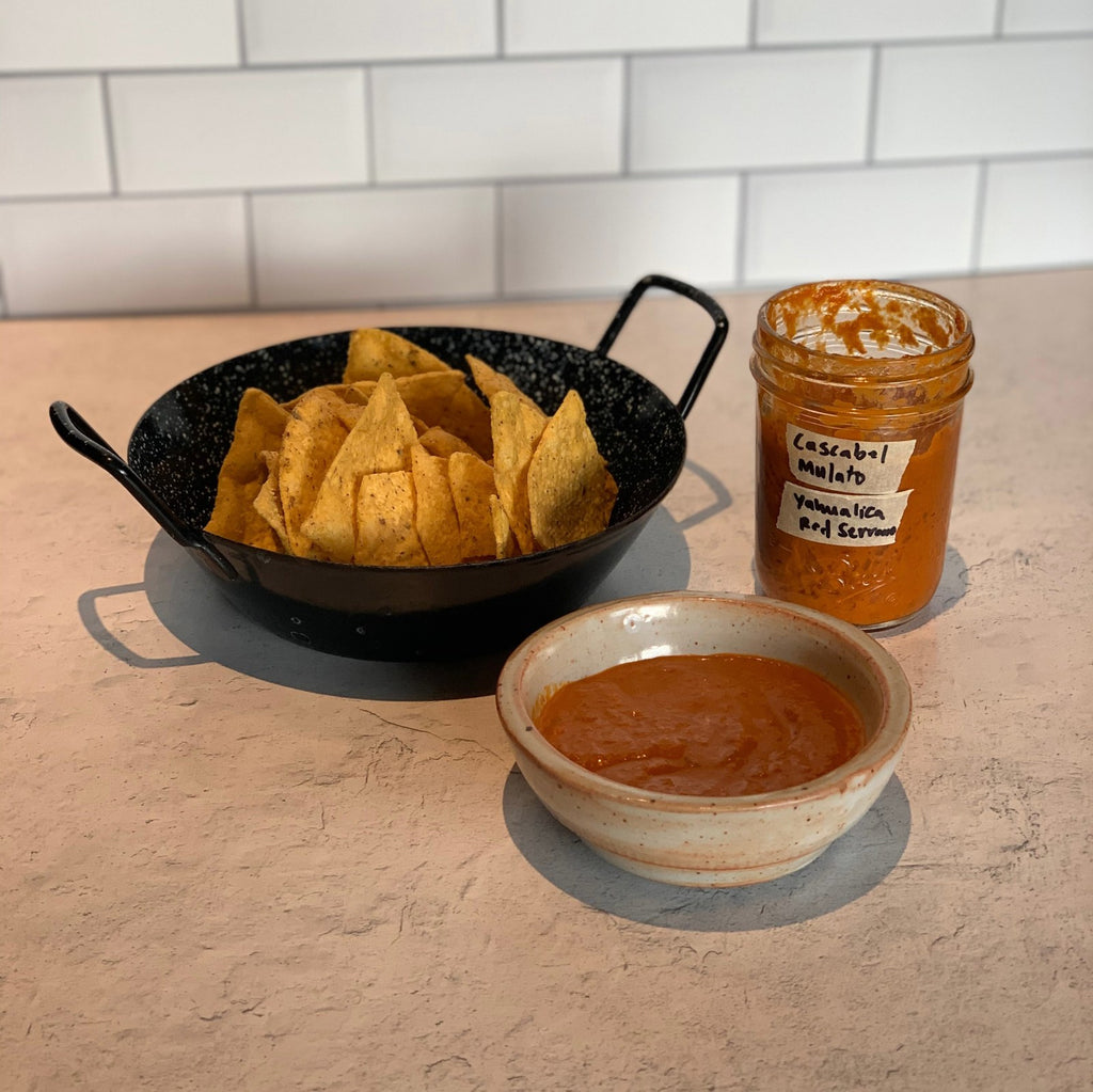 bowl of tortilla chips, a bowl of salsa and a jar of salsa