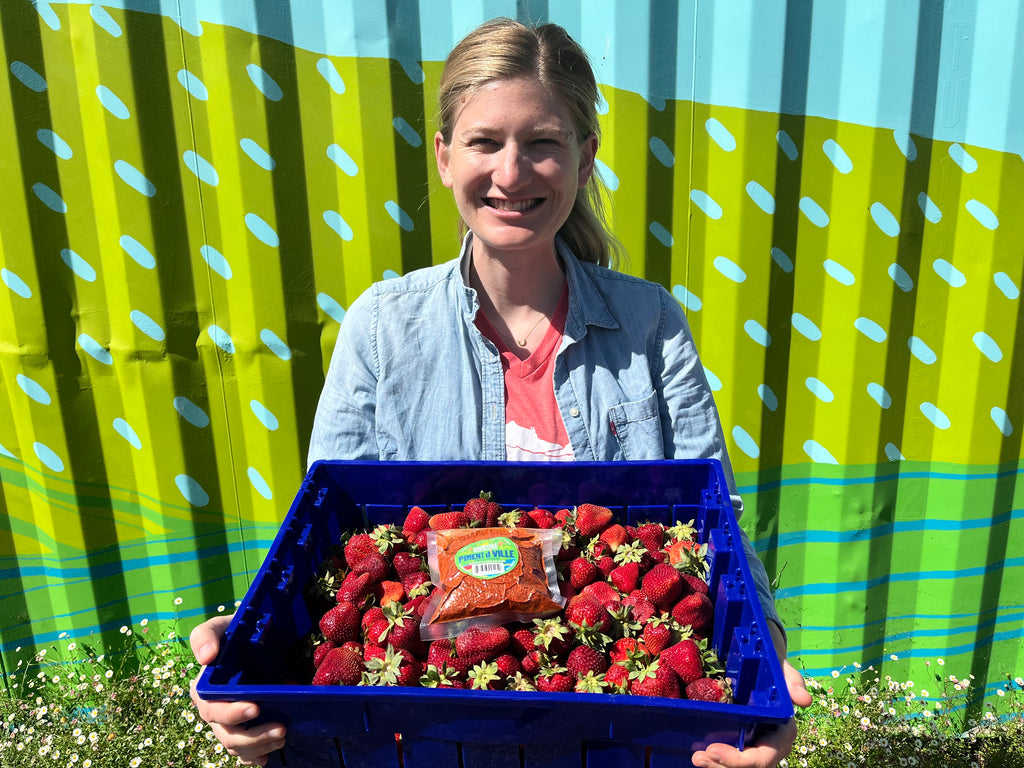 woman smiling and holding box of strawberries